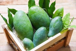 Fresh green mango and green leaves on wooden box top view harvest mango raw summer fruit photo