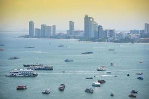 mar de la zona de la bahía con ferry y vistas de viajes turísticos construyendo un hito de fondo en la ciudad de pattaya foto