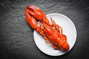 Langosta en un plato blanco con fondo oscuro - Gambas de camarón de marisco foto