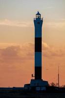 dungeness, kent, reino unido, 2008. puesta de sol detrás del faro en la playa foto