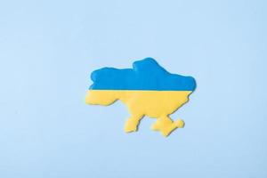 Shape of Ukraine in yellow-blue colors of the national flag on a blue background top view photo