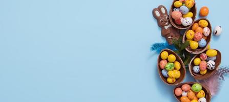 Banner Easter hunt concept with flat lay chocolate eggs and bunny on blue background. View from above