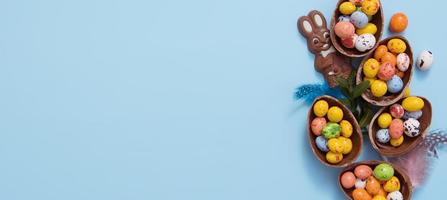 Banner Easter hunt concept with flat lay chocolate eggs and bunny on blue background. View from above photo