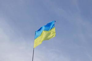 la bandera amarilla y azul ucraniana se desarrolla en el viento contra el cielo foto