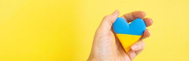 Yellow and blue heart in the colors of the flag of Ukraine in the hand of a woman photo