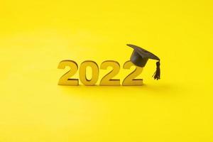 Graduated hat or cap with wooden number 2022 on a yellow background. Class 2022 concept photo