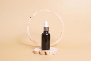 Wooden podium or pedestal with a dropper bottles of cosmetics oil or serum. Neutral beige monochrome skin care concept photo