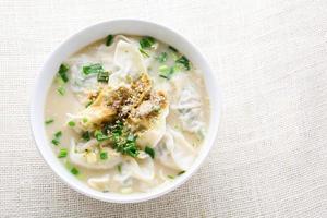 sopa wonton con cebolleta servida en un tazón blanco, enfoque selectivo foto