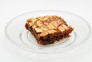 Chocolate brownie with almond topping on glass plated photo