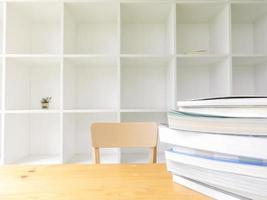 estantería blanca de madera moderna con algunos libros sobre mesa de madera, fondo de biblioteca en el interior, decoración limpia y moderna. foto