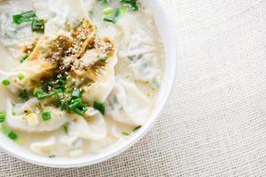 sopa wonton con cebolleta servida en un tazón blanco, enfoque selectivo foto