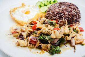 Spicy stir fried squid with basil leaves and chili, Sunny side up egg, served with brown rice. It is famous Thai food. You can change material designed and try to cook for your family. photo