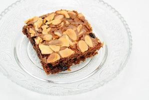 Chocolate brownie with almond topping on glass plated photo