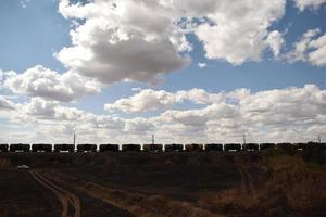 a long freight train rides under a cloudy sky