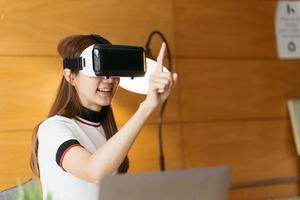 Woman wearing virtual reality goggles standing in a office. VR glasses. 360 degrees. Virtual reality headset. VR game. Wearing virtual reality goggles. Smartphone with VR. Virtual reality video. photo
