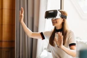 Woman in VR glasses. Confident young woman in virtual reality headset pointing in the air while sitting at her working place in office photo