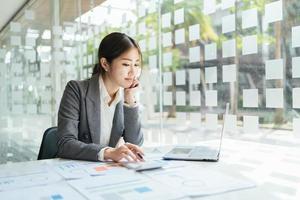 asian accountant woman working about financial with business report and calculator.financial or accounting concept. photo