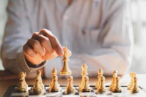 mano de hombre de negocios moviendo la figura del rey del ajedrez dorado y el oponente de jaque mate durante la competencia de tablero de ajedrez. concepto de estrategia, éxito, gestión, planificación empresarial, disrupción y liderazgo