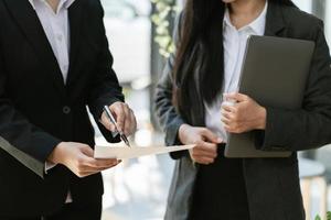 Two businessmen deep in discussion together while standing in an office with windows. photo