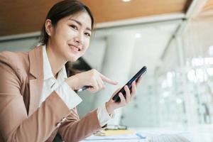 Asian woman using smart phone and laptop in office. photo