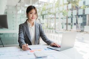 Asian woman working in the office using a laptop. photo