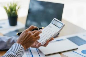 concepto de contabilidad empresarial, hombre de negocios que usa calculadora con computadora portátil, presupuesto y papel de préstamo en la oficina. foto