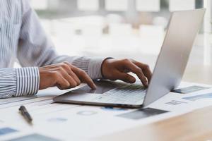 Manager is using a laptop computer while analyzing the company's financial statements on the screen. photo