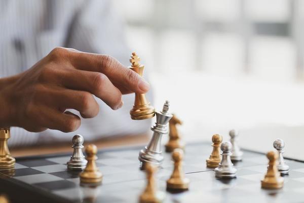 Close up of hands of a business man moving king golden chess to defeat  opponent the chess game is development analysis, strategy, and plan, the  management or leadership concept. 22804709 Stock Photo