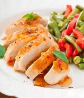 Chicken breast with vegetables and sauce decorated with basil leaves photo