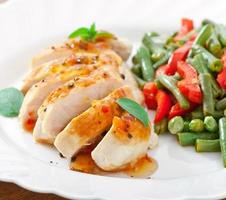 Chicken breast with vegetables and sauce decorated with basil leaves photo