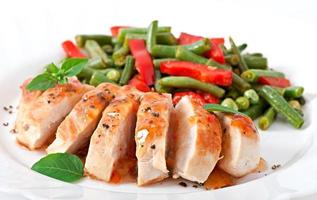 Chicken breast with vegetables and sauce decorated with basil leaves photo