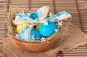 Easter eggs in nest on wooden background photo