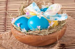 Easter eggs in nest on wooden background photo