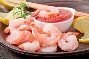 tails of shrimps with fresh lemon and rosemary in plate on wooden old background photo