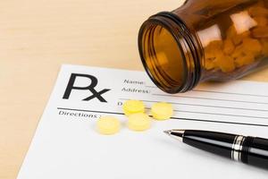 Medicine on blank prescription form with pen focus on pill photo