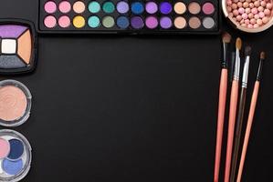 Frame of cosmetics on black background and make up tools. Top view and mock up. Copy space. photo