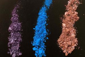 Eye shadows on black background. Crushed cosmetic. Make up cosmetics. Top view and mock up photo