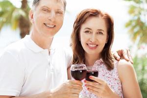 Lovely middle age couple with wine glass in tropical background - close up photo