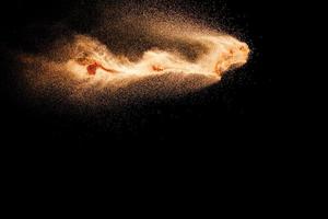 Abstract sand cloud.Brown sand splash against dark background. Brown dust explosion. photo