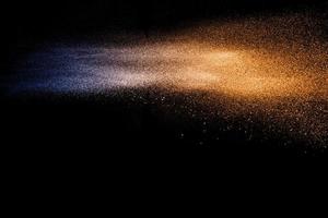 Blue orange dust particles explosion on black background. Color powder dust splash. photo