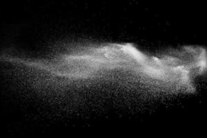 Freeze motion of white dust particles on black background. White powder explosion. photo