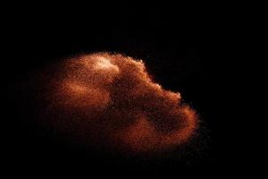 Fondo de arena marrón borroso de movimiento abstracto. Explosión de arena aislada sobre fondo oscuro. foto