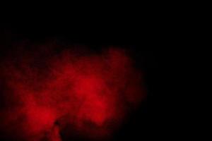 Red powder explosion cloud on black background. Freeze motion of red color dust  particles splashing. photo