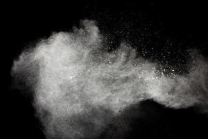 Freeze motion of white dust particles splash on black background. photo