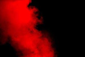 Red powder explosion on black background. Freeze motion of red dust particles splash. photo