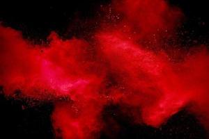 Red powder explosion on black background. Freeze motion of red dust particles splash. photo