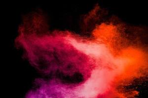 Red pink color powder explosion on black background.Freeze motion of red dust particles splashing. photo