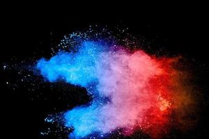 Multicolored powder explosion on black background. Blue pink and orange dust splashing. photo