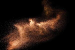 Abstract sand cloud.Brown sand splash against dark background. Brown dust explosion. photo