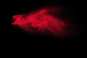 Red powder explosion on black background. Freeze motion of Red dust particles splash. photo